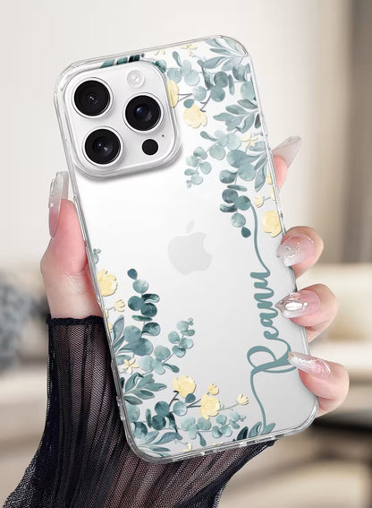 Custom name Reanu printed vertically in teal script on a clear silicone phone case featuring a watercolor eucalyptus and yellow floral design.