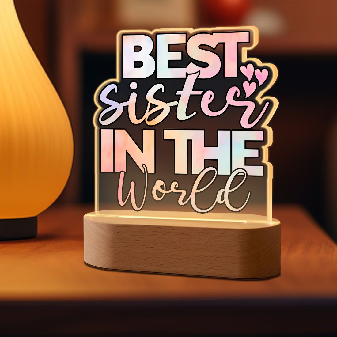 Side view of Best Sister in the World acrylic LED lamp with pastel typography on wooden base