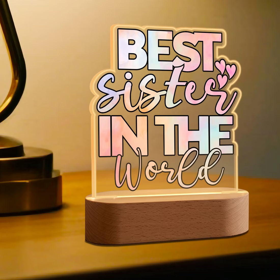Side view of Best Sister in the World acrylic LED lamp with pastel typography on wooden base