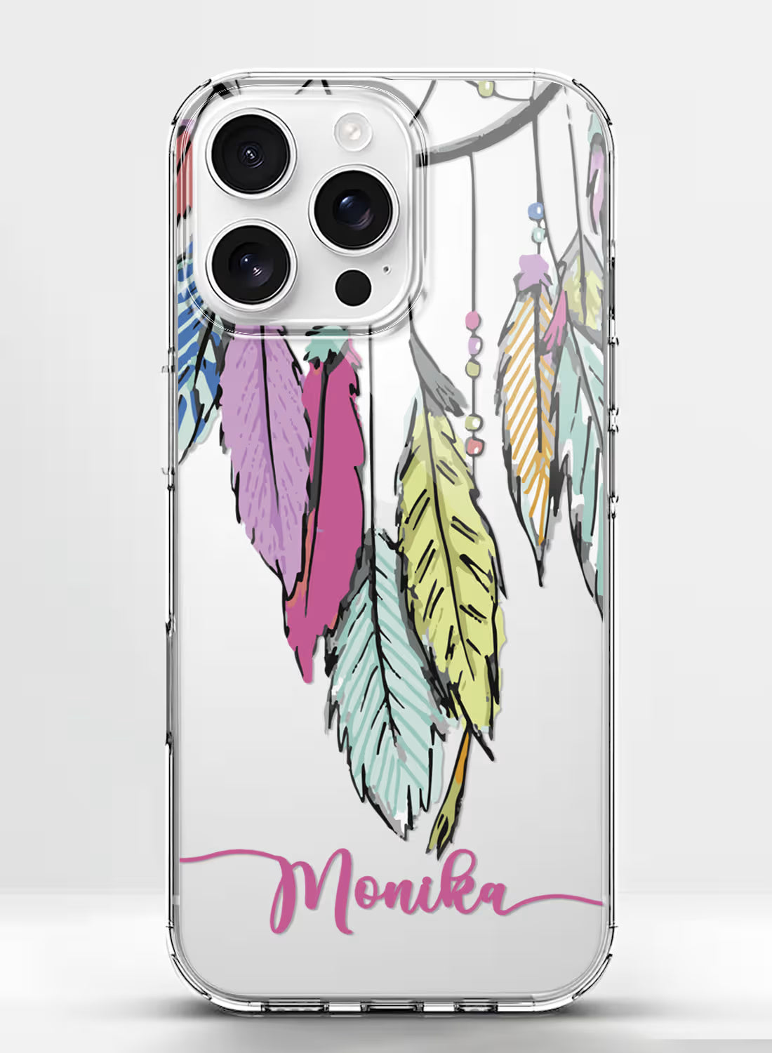 Custom name Monika in pink script on a clear silicone phone case featuring a colorful boho hanging feathers design.