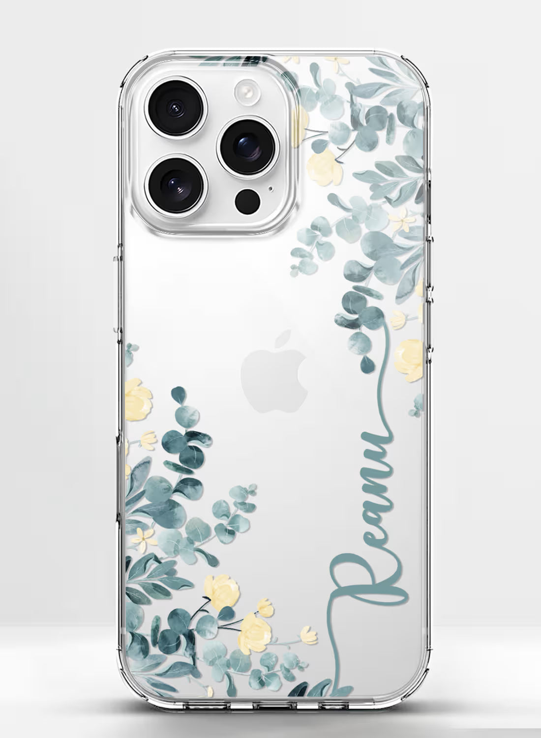 Custom name Reanu printed vertically in teal script on a clear silicone phone case featuring a watercolor eucalyptus and yellow floral design.